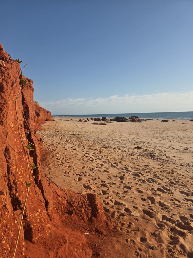 Red cliffs meeting a sandy beach and the ocean on the Broome coastline